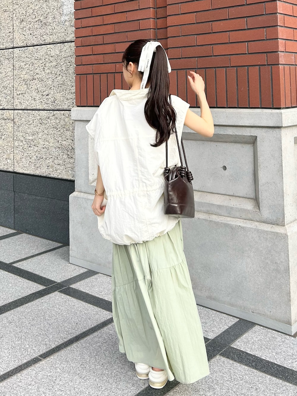 ブラウン系のショルダーバッグ、ホワイト系のミリタリージャケット、ホワイト系のキャミソールを着用したレディースの秋コーディネートの4枚目の写真