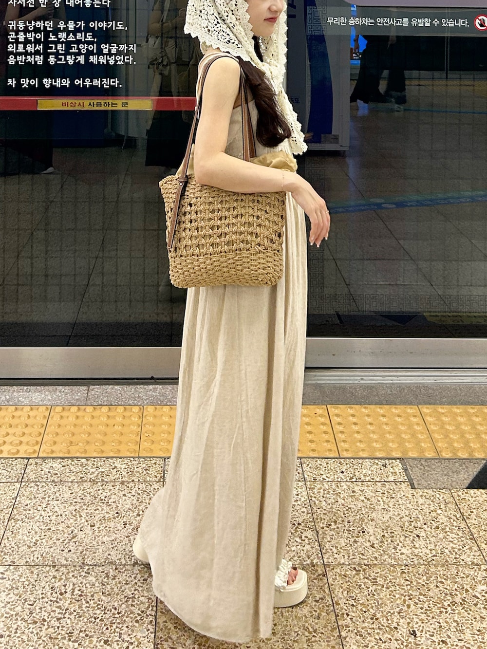 ベージュ系のワンピース/ドレス、ブラウン系のかごバッグ、ホワイト系のサンダルを着用したレディースの夏コーディネートの2枚目の写真