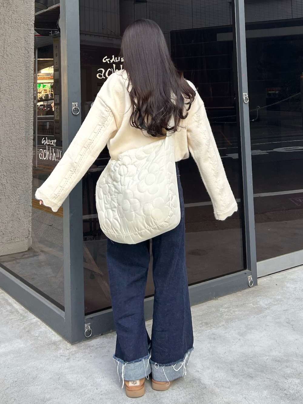 ブルー系のデニムパンツ、ホワイト系のショルダーバッグ、ホワイト系のニット/セーターを着用したレディースの秋コーディネートの2枚目の写真