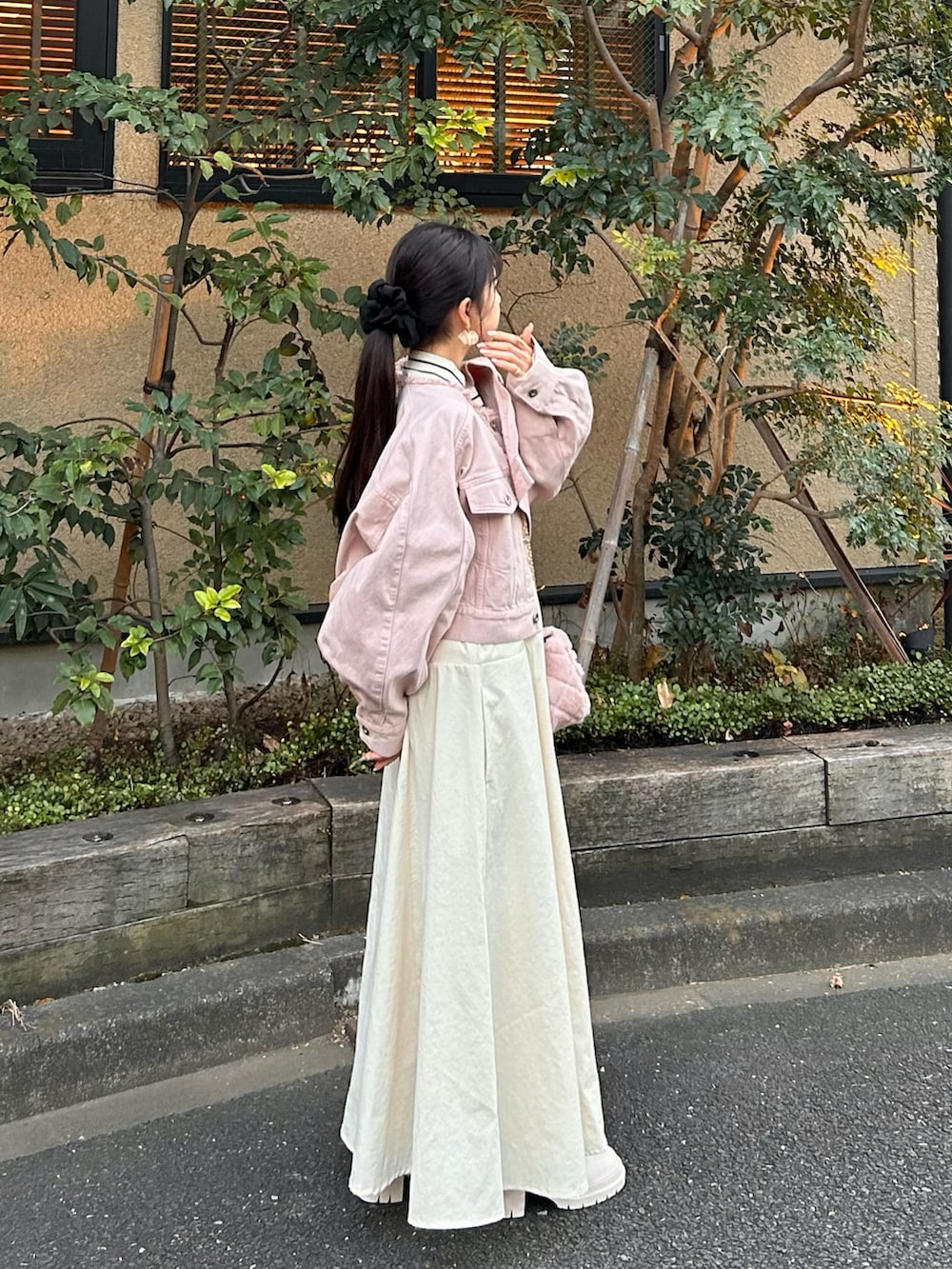 ピンク系のデニムジャケット、ホワイト系のワンピース、ホワイト系のブーツを着用したレディースの冬コーディネートの3枚目の写真