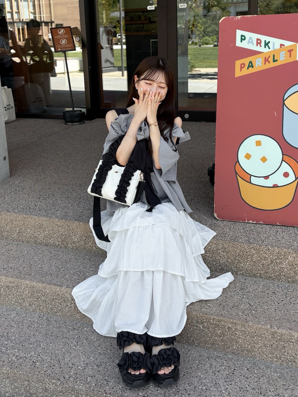 グレー系のシャツ/ブラウス、ブラック系のサンダル、ホワイト系のスカートを着用したレディースの夏コーディネートの2枚目の写真