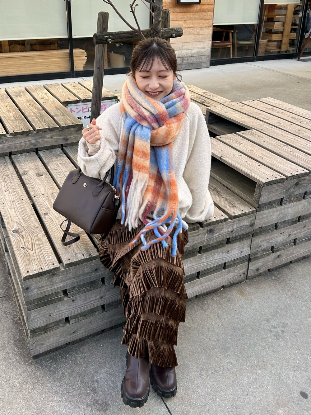 ブラウン系のバッグ、ブラウン系のスカート、ブラウン系のブーツを着用したレディースの冬コーディネートの3枚目の写真