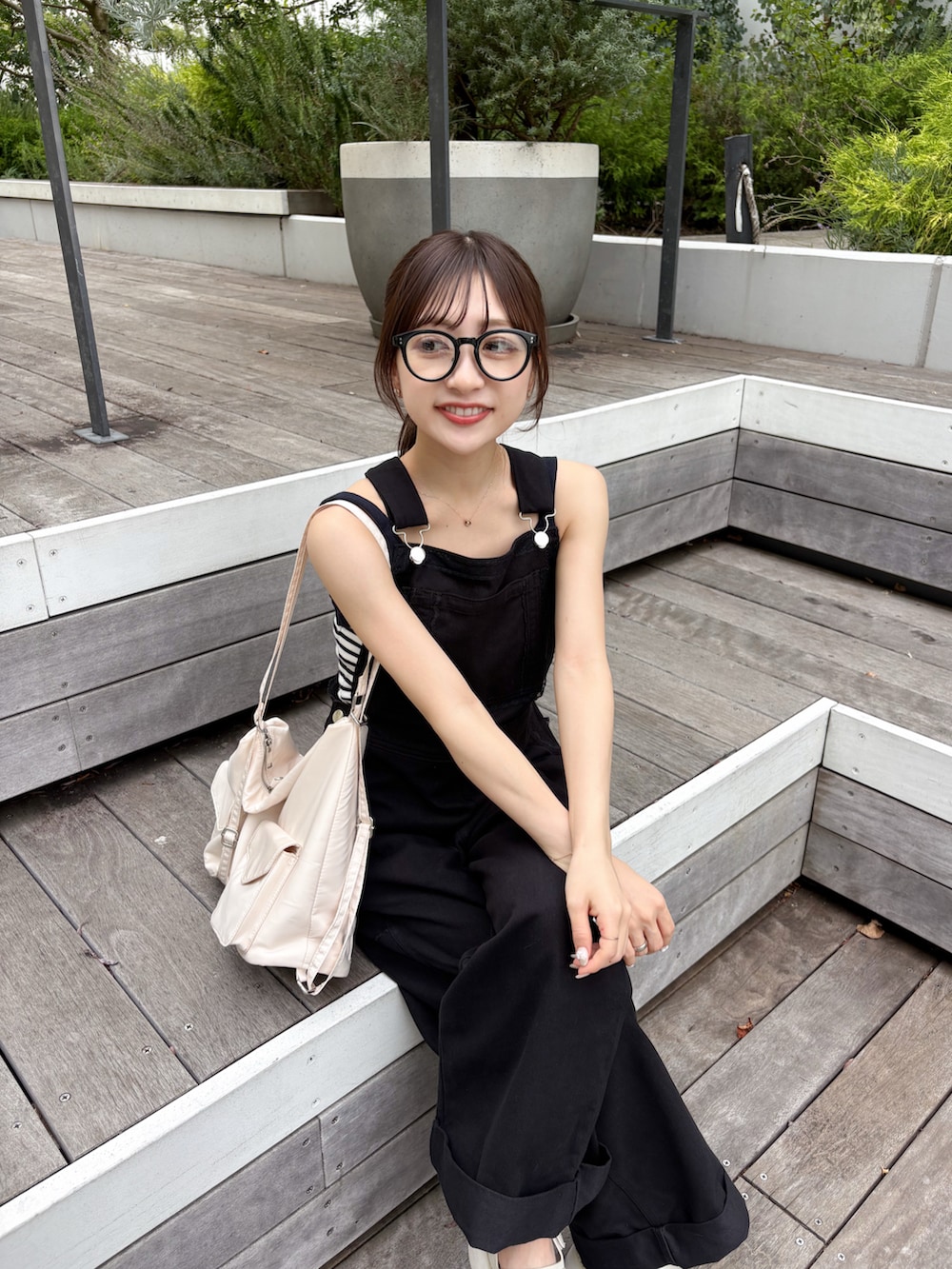 ホワイト系のトートバッグ、ブラック系のデニムパンツ、ホワイト系のサンダルを着用したレディースの夏コーディネートの2枚目の写真
