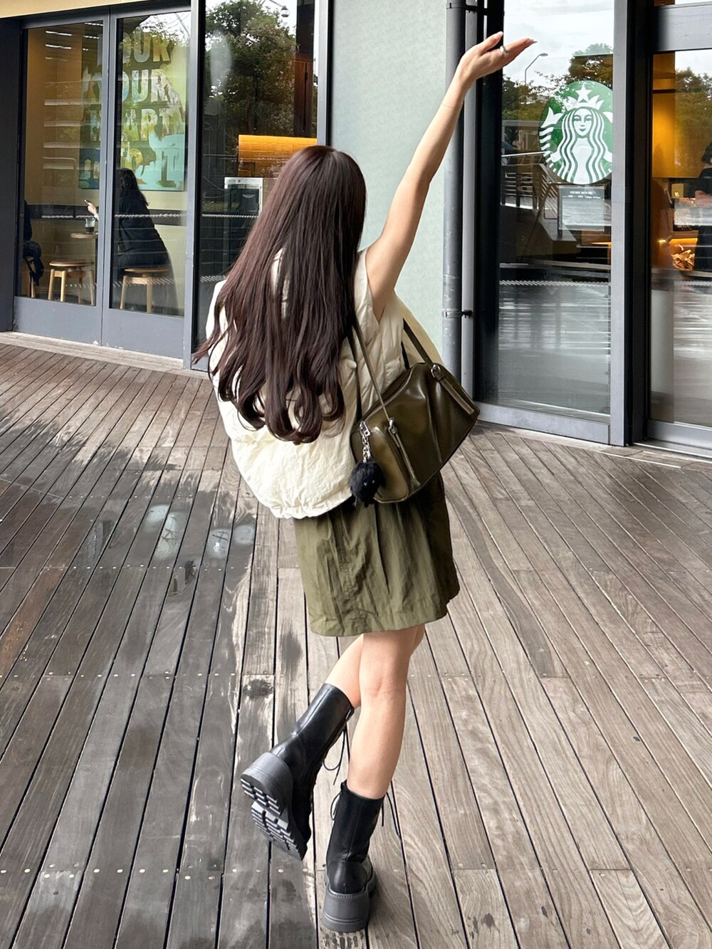 グリーン系のトートバッグ、グリーン系のスカート、ホワイト系のTシャツ/カットソーを着用したレディースの秋コーディネートの2枚目の写真