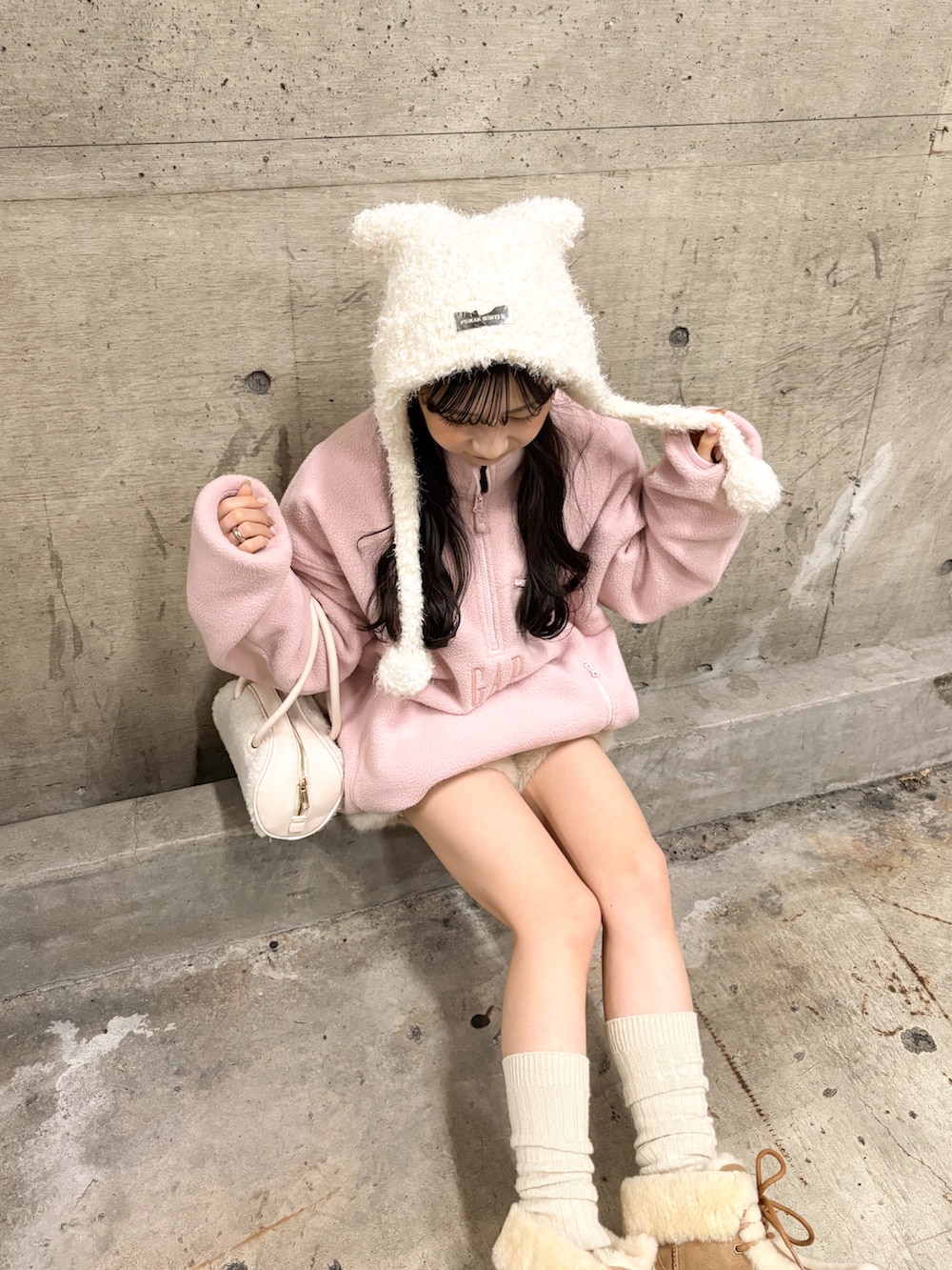 ピンク系のスウェット、ホワイト系のボストンバッグ、ベージュ系のブーツを着用したレディースの冬コーディネートの2枚目の写真