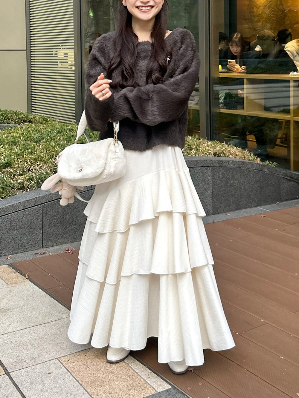 ホワイト系のショルダーバッグ、ピンク系のワンピース、ブラウン系のカーディガン/ボレロを着用したレディースの冬コーディネートの4枚目の写真