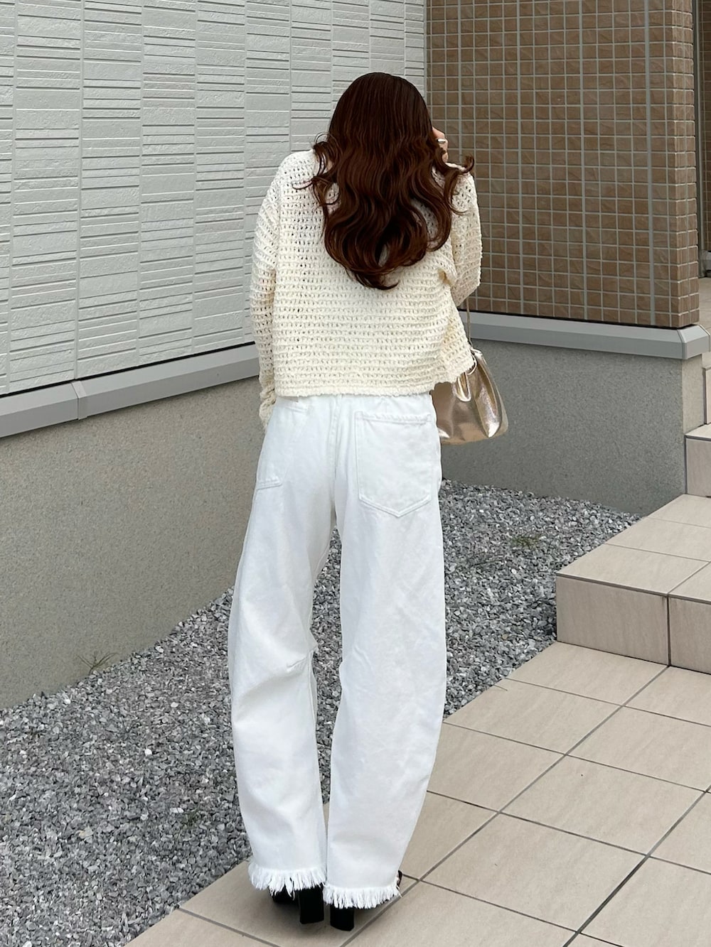 ホワイト系のデニムパンツ、ホワイト系のニット/セーター、ゴールド系のショルダーバッグを着用したレディースの春コーディネートの4枚目の写真