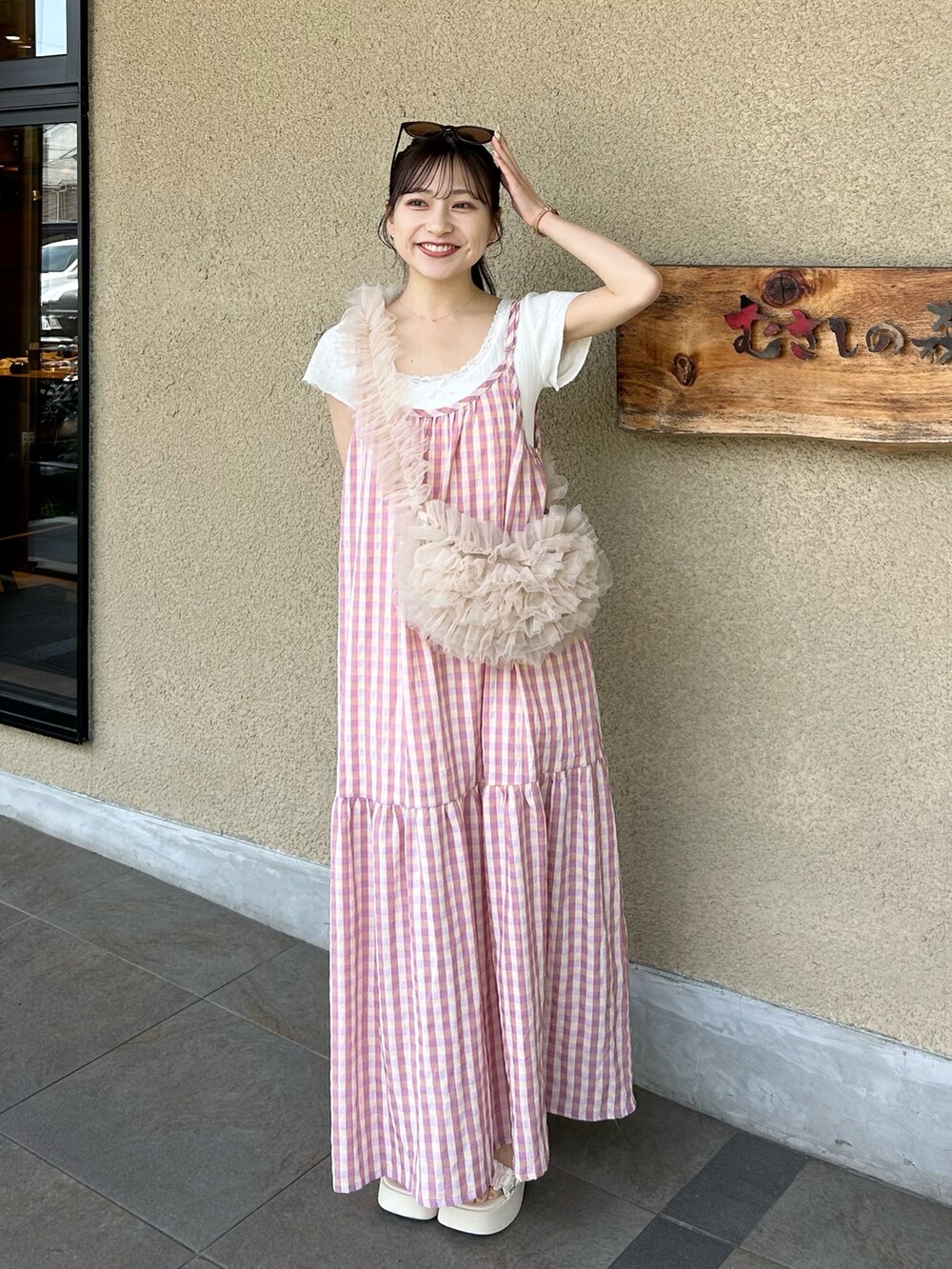 ピンク系のハンドバッグ、ホワイト系のサンダル、ホワイト系のトップスを着用したレディースの夏コーディネートの4枚目の写真