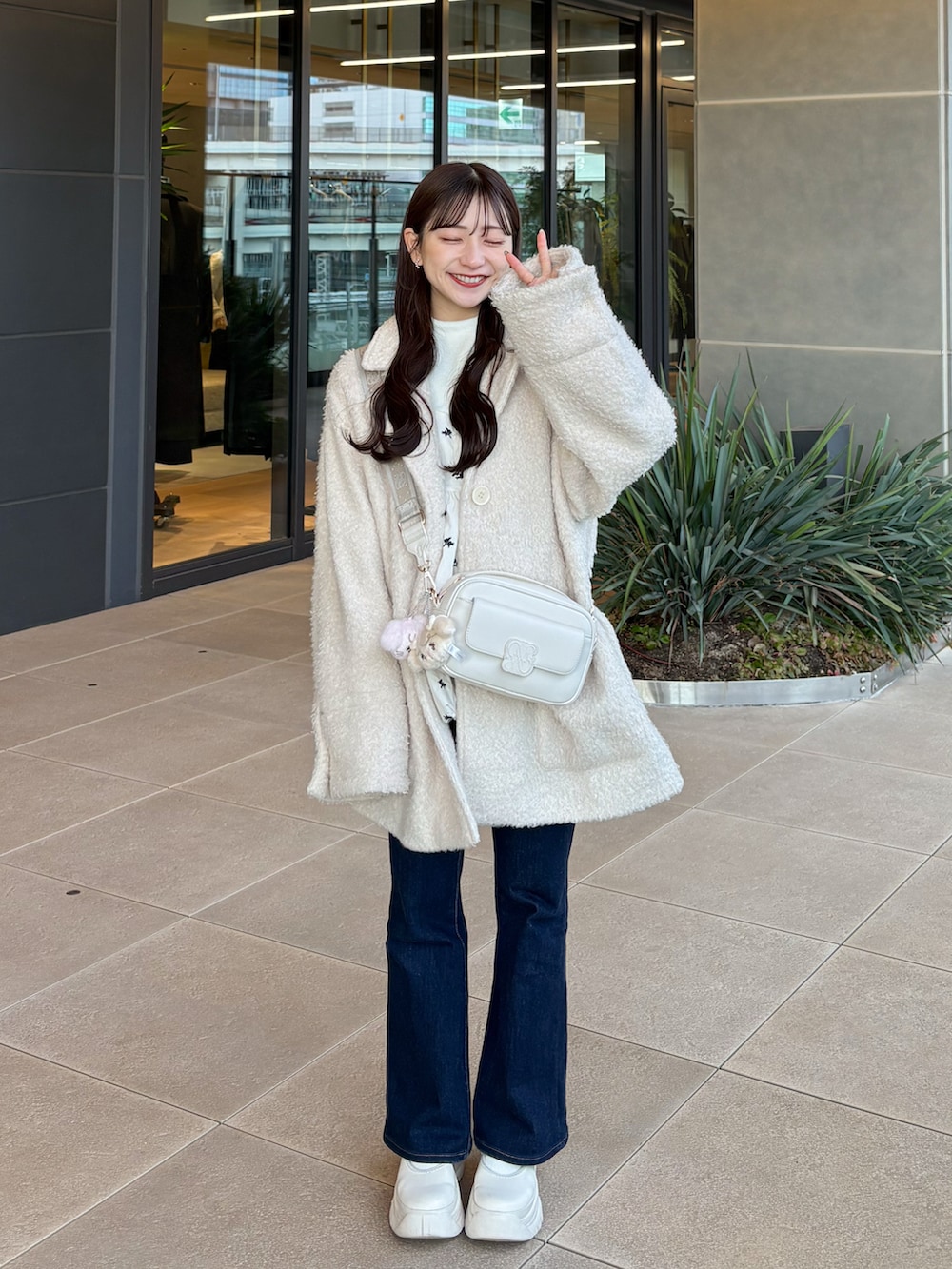 ブルー系のデニムパンツ、ホワイト系のシューズ、ホワイト系のショルダーバッグを着用したレディースの冬コーディネートの5枚目の写真