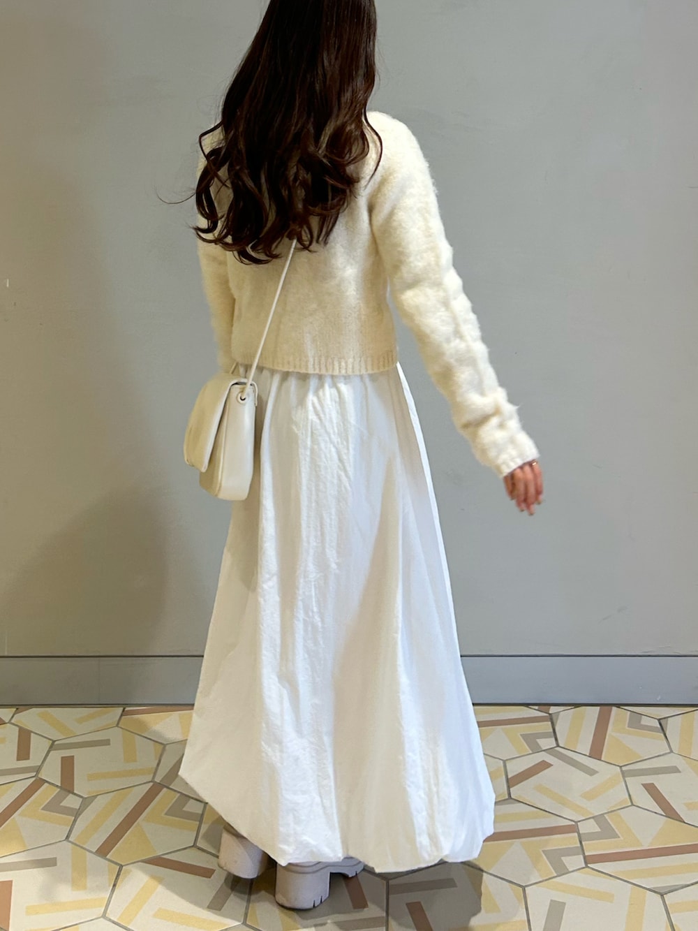ホワイト系のカーディガン/ボレロ、ホワイト系のショルダーバッグ、ホワイト系のスカートを着用したレディースの冬コーディネートの2枚目の写真