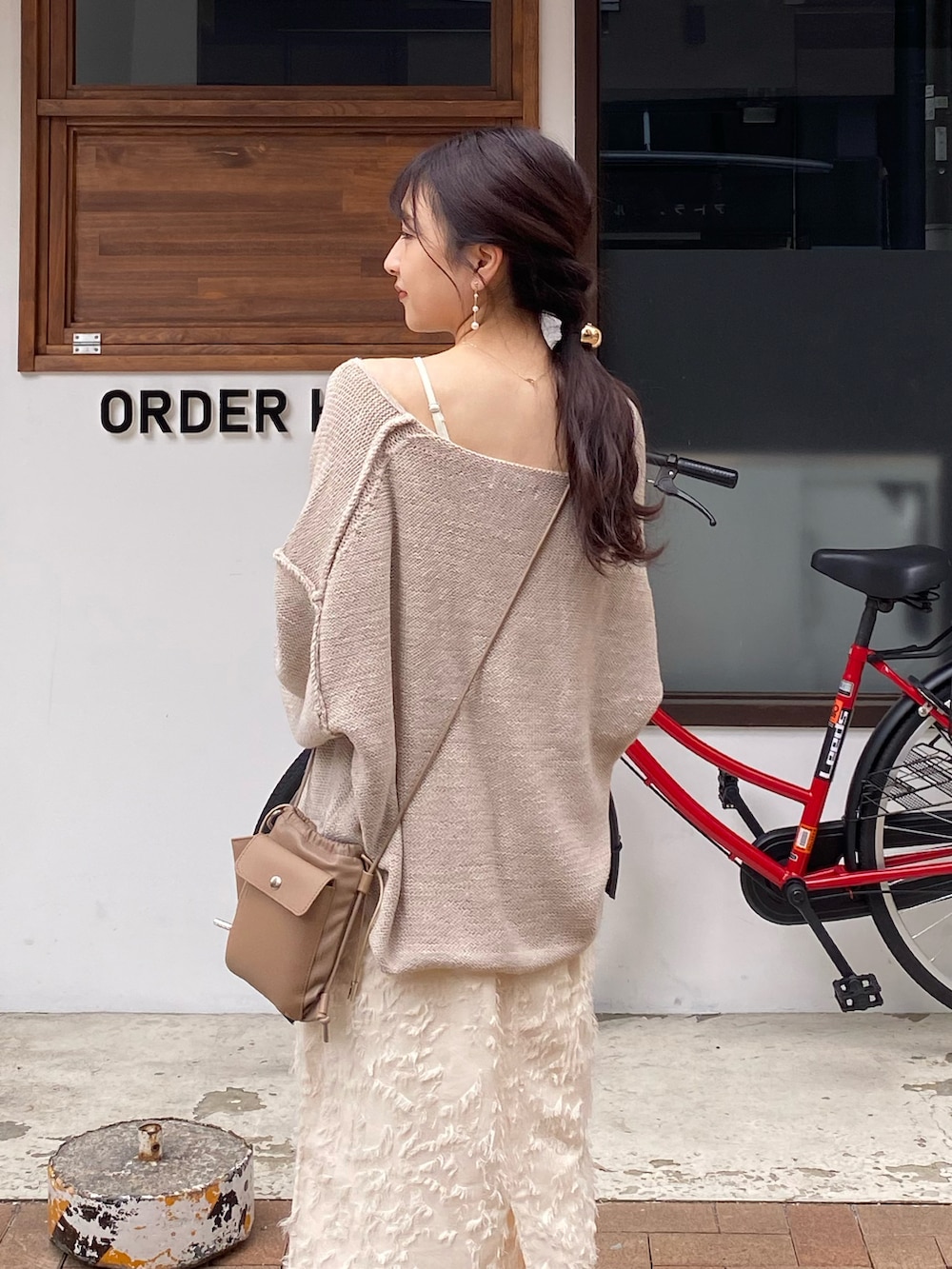 ベージュ系のショルダーバッグ、ベージュ系のニット/セーター、ホワイト系のスカートを着用したレディースの秋コーディネートの3枚目の写真