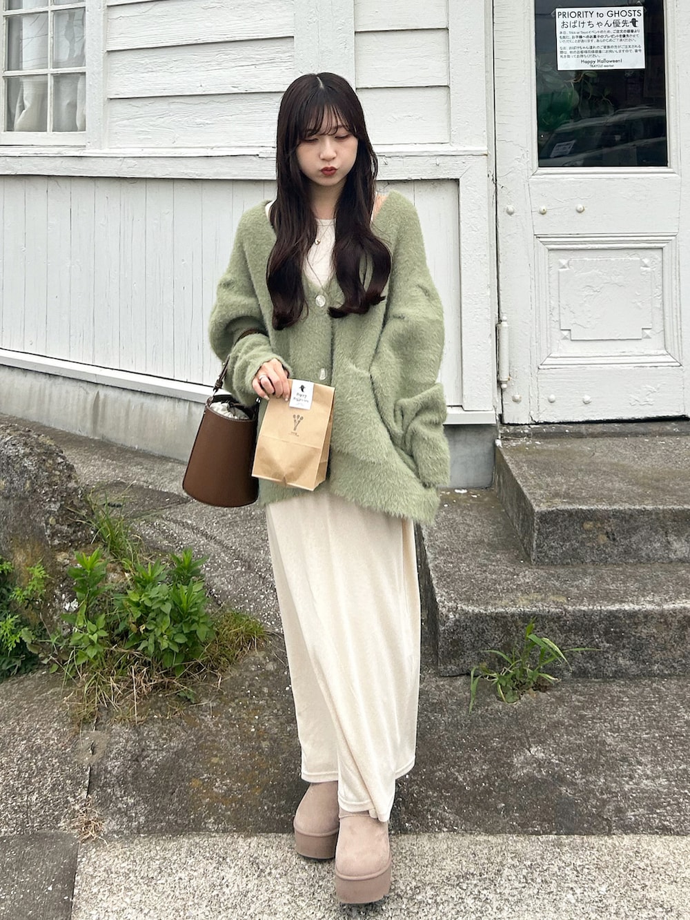 グリーン系のカーディガン/ボレロ、ブラウン系のハンドバッグ、ベージュ系のワンピースを着用したレディースの秋コーディネートの3枚目の写真