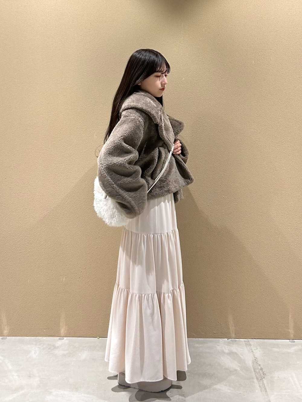 ブラウン系のブルゾン、ピンク系のTシャツ/カットソー、ホワイト系のスカートを着用したレディースの冬コーディネートの2枚目の写真