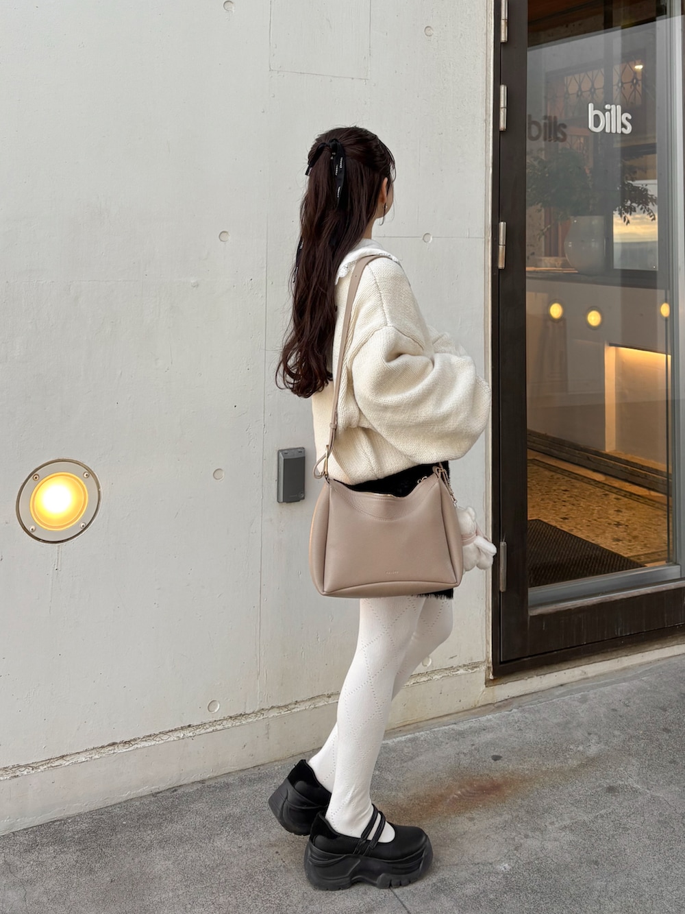 ブラック系のサンダル、ブラック系のスカート、ホワイト系のニット/セーターを着用したレディースの冬コーディネートの2枚目の写真