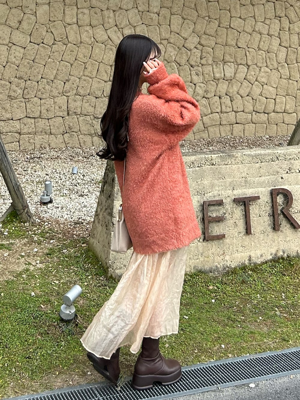 ホワイト系のその他アウター、ブラウン系のブーツ、オレンジ系のカーディガン/ボレロを着用したレディースの冬コーディネートの4枚目の写真