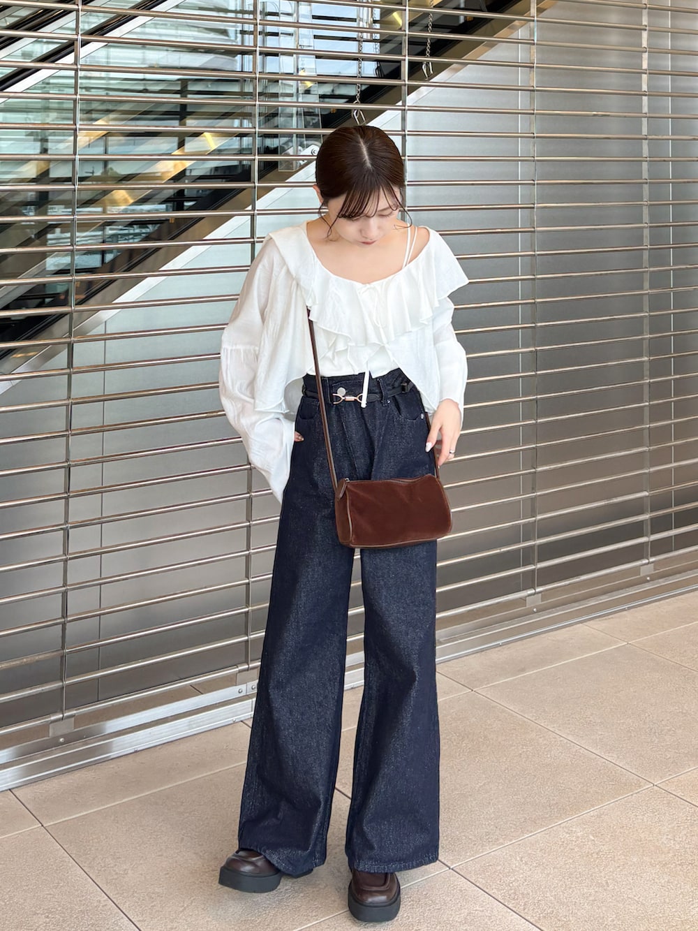 ブルー系のデニムパンツ、ブラウン系のローファー、ホワイト系のシャツ/ブラウスを着用したレディースの秋コーディネートの4枚目の写真