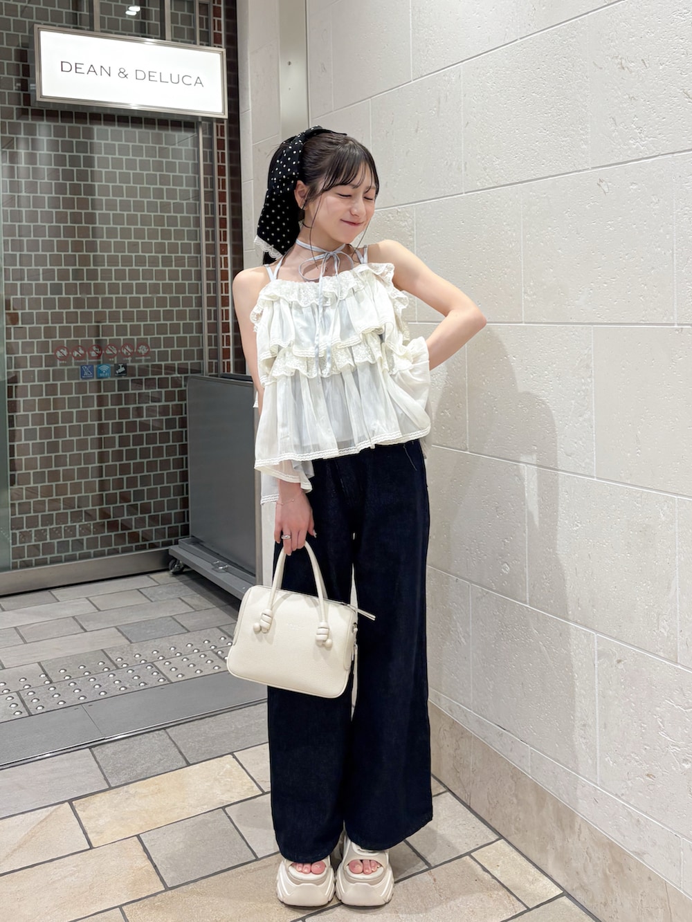 ホワイト系のハンドバッグ、ブルー系のデニムパンツ、ホワイト系のトップスを着用したレディースの夏コーディネートの3枚目の写真