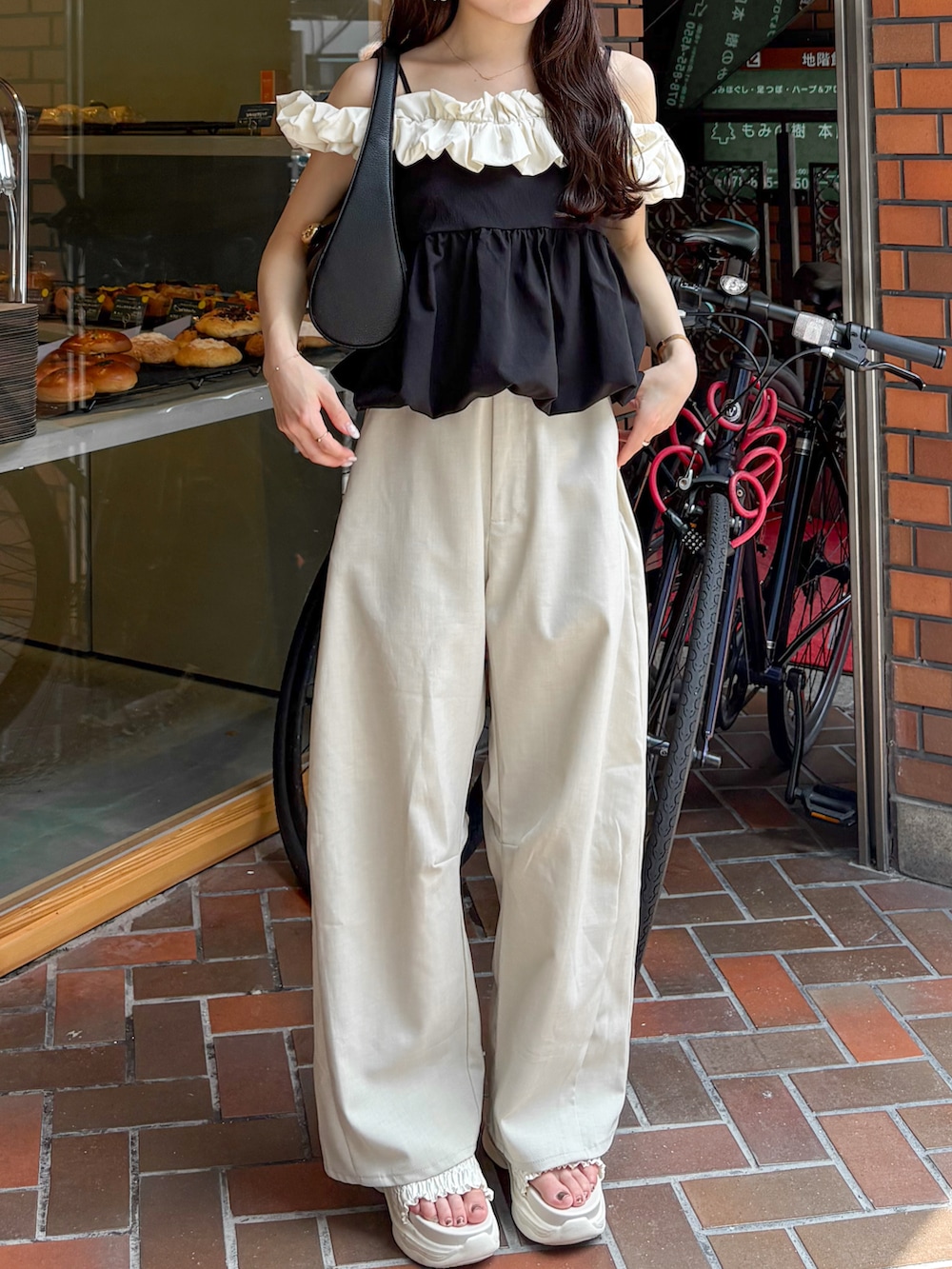 ホワイト系のスラックス、ホワイト系のサンダル、ホワイト系のトップスを着用したレディースの夏コーディネートの4枚目の写真