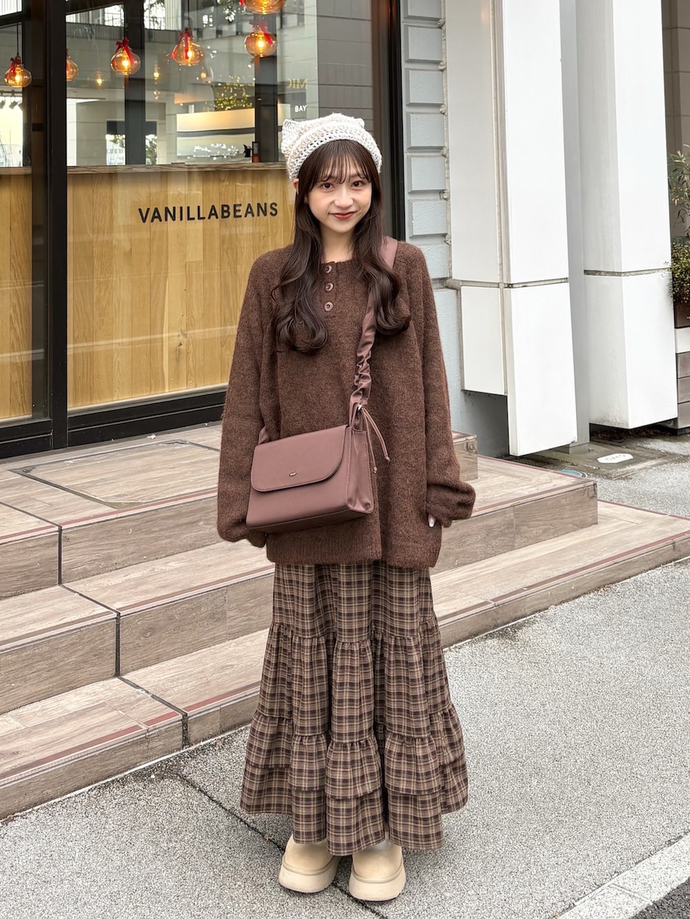 ブラウン系のニット/セーター、ブラウン系のスカート、ホワイト系のその他アウターを着用したレディースの冬コーディネートの5枚目の写真