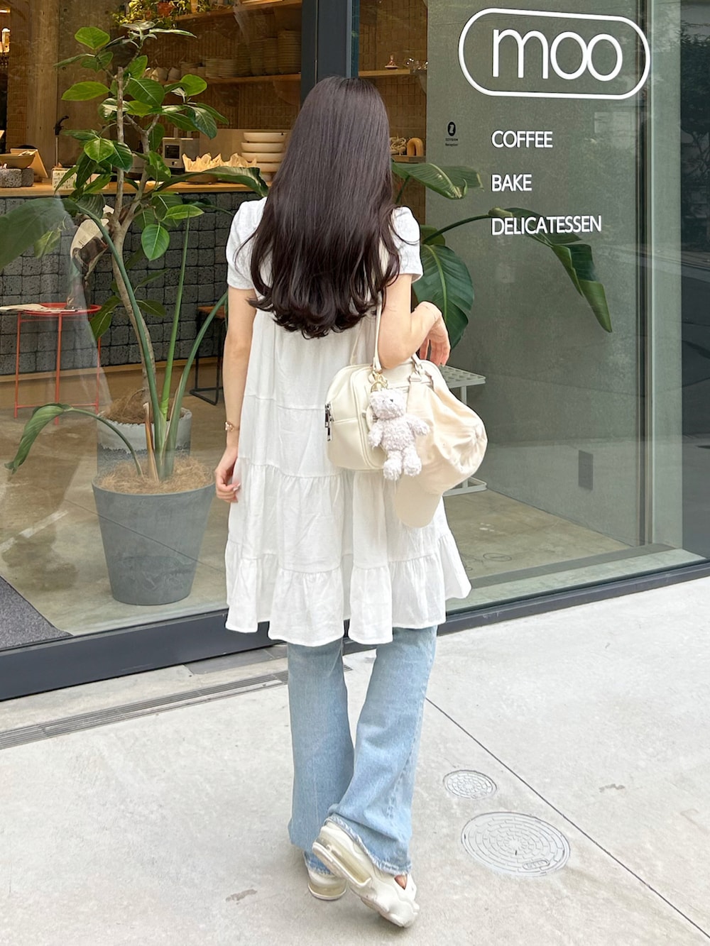 ブルー系のデニムパンツ、ホワイト系のワンピース、ホワイト系のショルダーバッグを着用したレディースの夏コーディネートの2枚目の写真