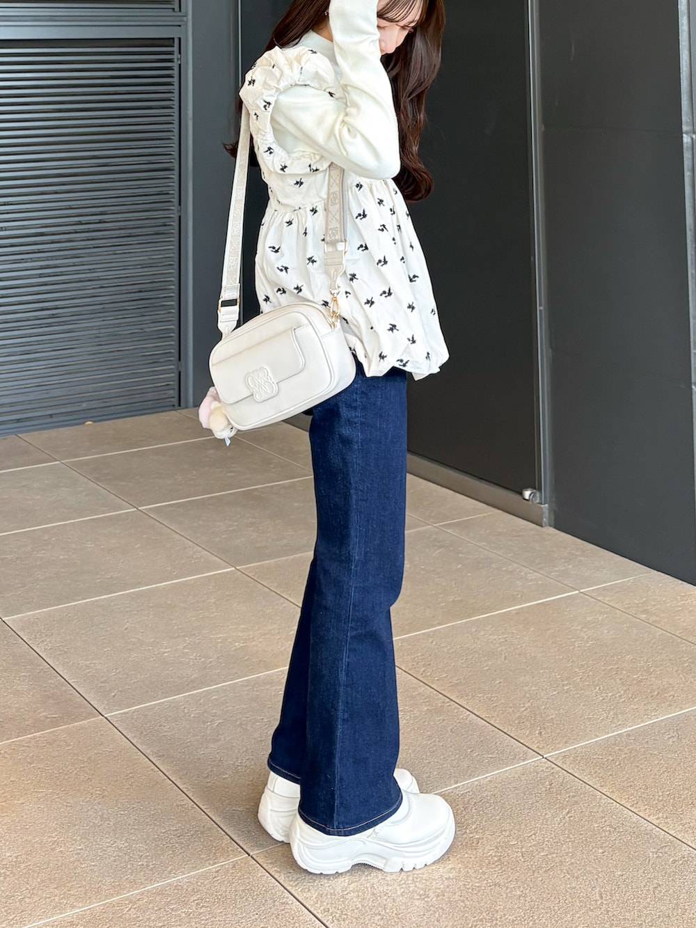 ブルー系のデニムパンツ、ホワイト系のシューズ、ホワイト系のショルダーバッグを着用したレディースの冬コーディネートの4枚目の写真