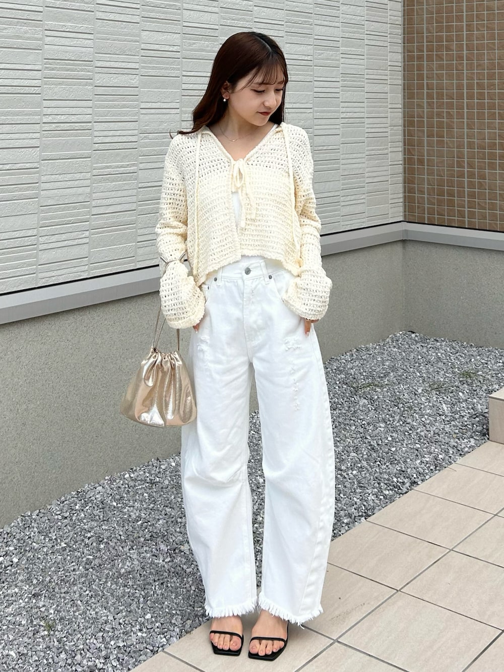 ホワイト系のデニムパンツ、ホワイト系のニット/セーター、ゴールド系のショルダーバッグを着用したレディースの春コーディネートの2枚目の写真