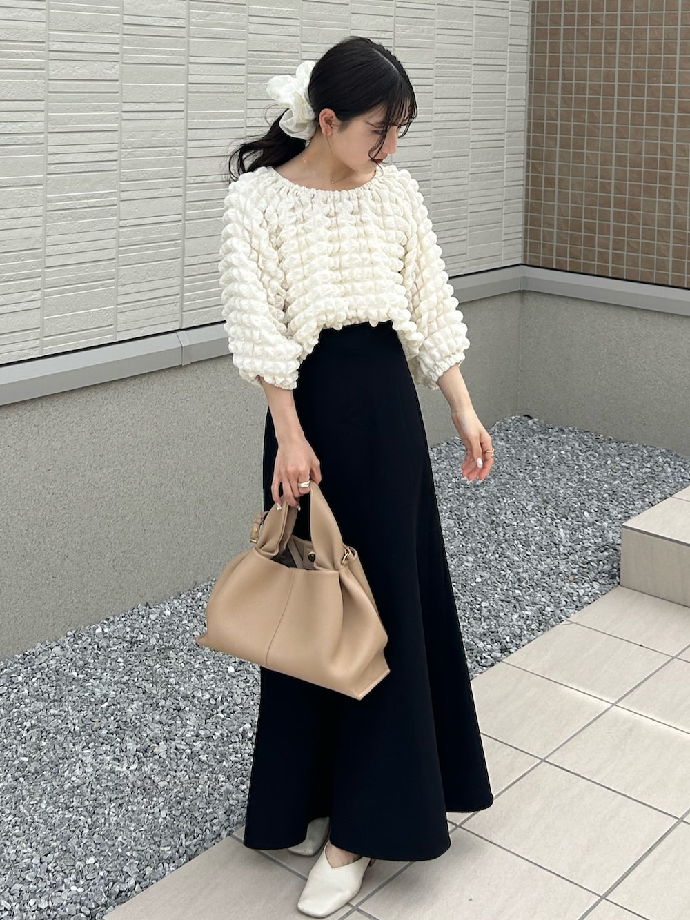 ベージュ系のバッグ、ホワイト系のTシャツ/カットソー、ブラック系のスカートを着用したレディースの春コーディネートの3枚目の写真
