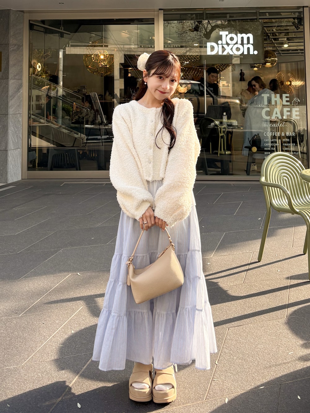 ホワイト系のトレンチコート、ホワイト系のカーディガン/ボレロ、ブルー系のスカートを着用したレディースの春コーディネートの2枚目の写真