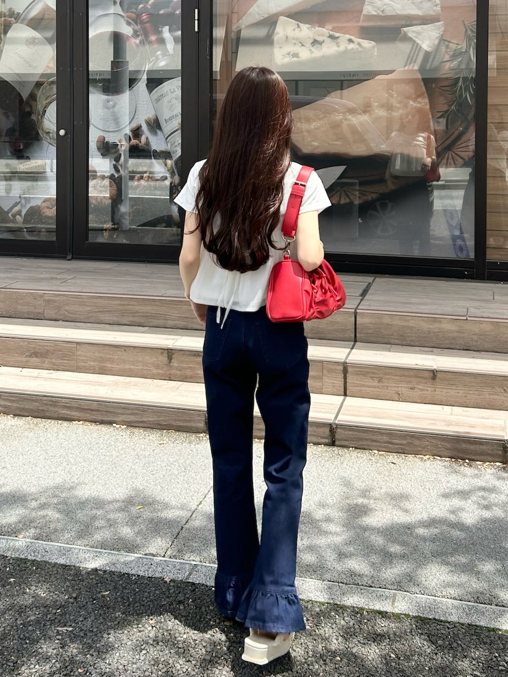 ブルー系のデニムパンツ、レッド系のショルダーバッグ、ホワイト系のTシャツ/カットソーを着用したレディースの夏コーディネートの4枚目の写真