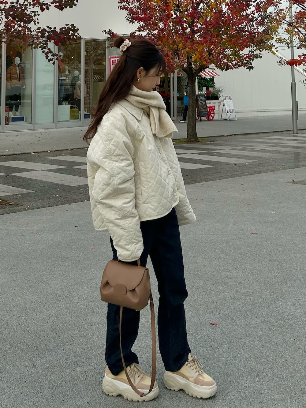 ブルー系のデニムパンツ、ブラウン系のバッグ、ホワイト系のジャケット/アウターを着用したレディースの秋コーディネートの2枚目の写真