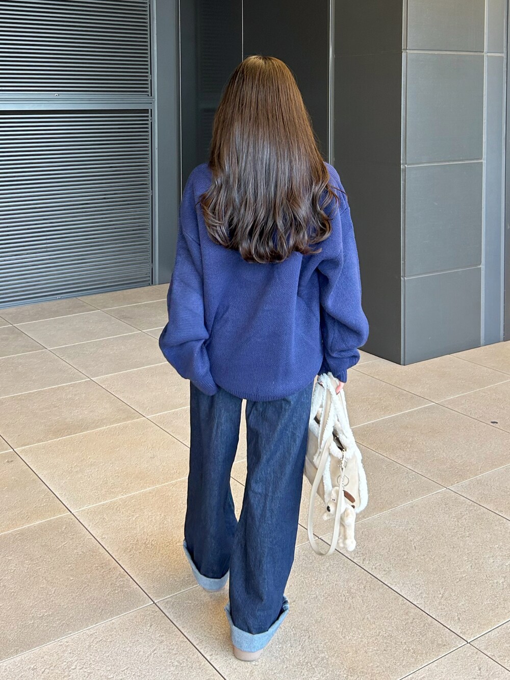 ベージュ系のトートバッグ、ブルー系のデニムパンツ、ベージュ系のブーツを着用したレディースの秋コーディネートの3枚目の写真