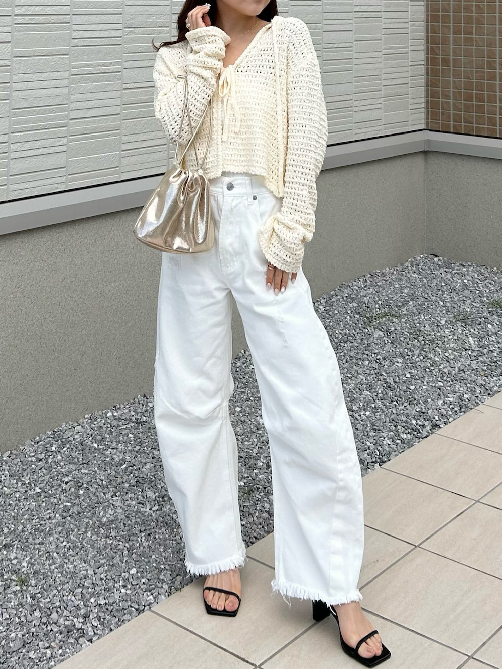 ホワイト系のデニムパンツ、ホワイト系のニット/セーター、ゴールド系のショルダーバッグを着用したレディースの春コーディネートの3枚目の写真