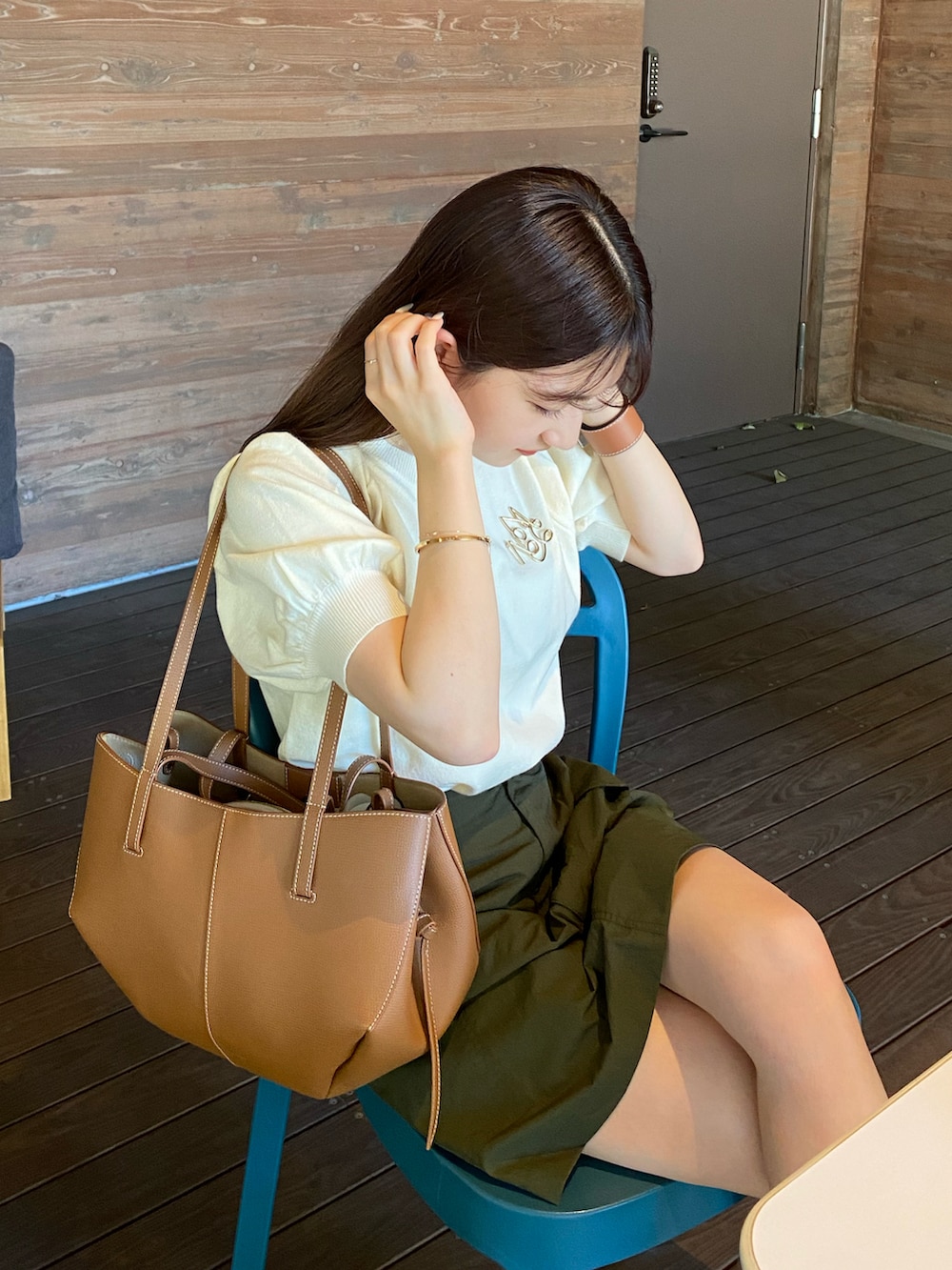 ホワイト系のニット/セーター、ブラウン系のバッグ、グリーン系のスカートを着用したレディースの夏コーディネートの3枚目の写真