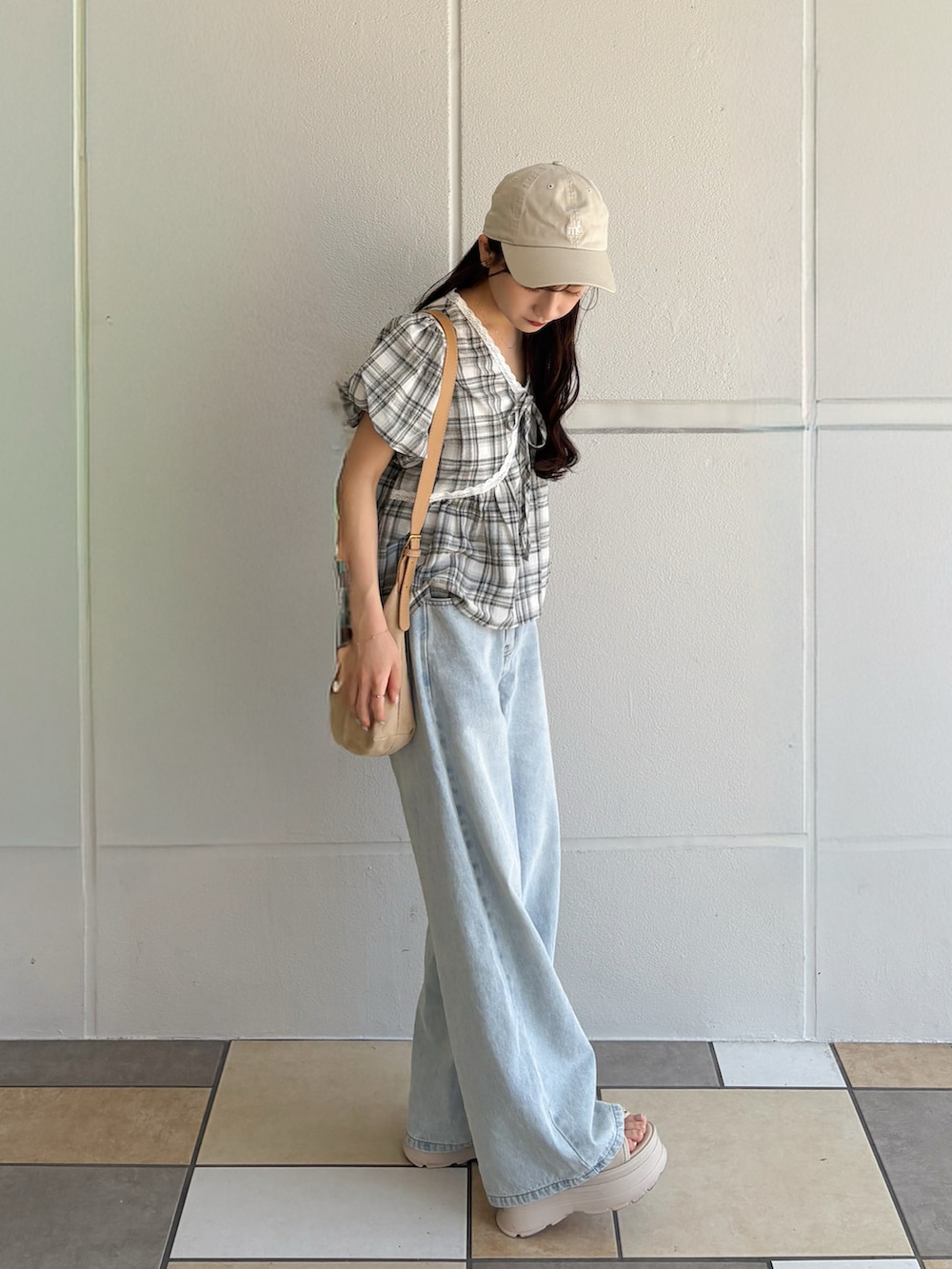 ブラック系のトップス、ベージュ系のショルダーバッグ、ブルー系のデニムパンツを着用したレディースの秋コーディネートの2枚目の写真