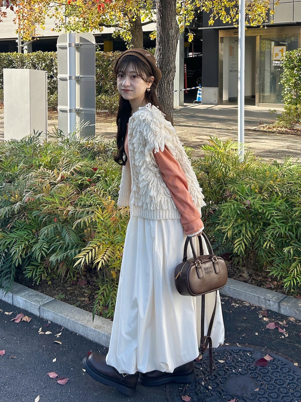 ブラウン系のバッグ、ホワイト系のスカート、ホワイト系のベストを着用したレディースの冬コーディネートの4枚目の写真
