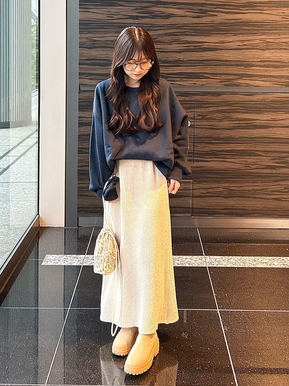 ホワイト系のスカート、ブルー系のスウェット、ベージュ系のショルダーバッグを着用したレディースの秋コーディネートの2枚目の写真