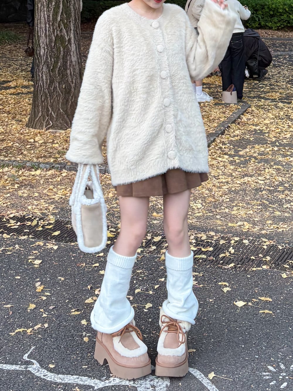 ベージュ系のブーツ、ベージュ系のカーディガン/ボレロ、ホワイト系のマフラーを着用したレディースの秋コーディネートの2枚目の写真