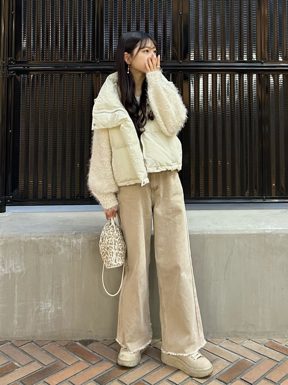 ベージュ系のデニムパンツ、ホワイト系のダウンベスト、ホワイト系のカーディガン/ボレロを着用したレディースの冬コーディネートの2枚目の写真