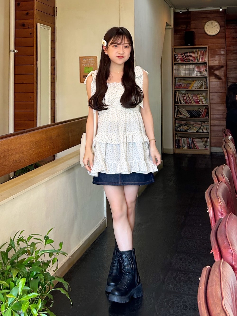 ブルー系のデニムスカート、ホワイト系のハンドバッグ、ブラック系のブーツを着用したレディースの秋コーディネートの2枚目の写真