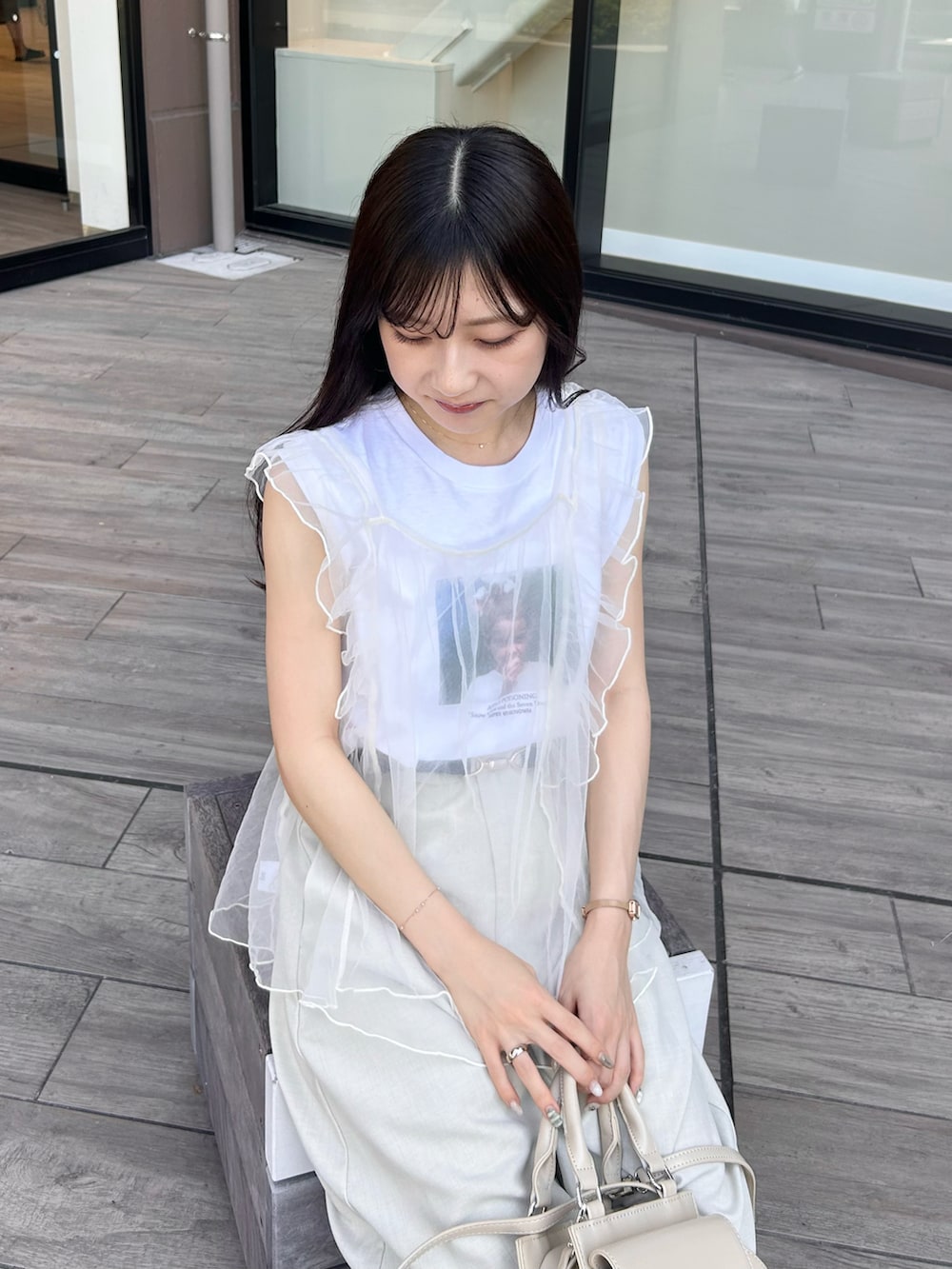 ベージュ系のハンドバッグ、ホワイト系のベスト、ホワイト系のTシャツ/カットソーを着用したレディースの夏コーディネートの3枚目の写真