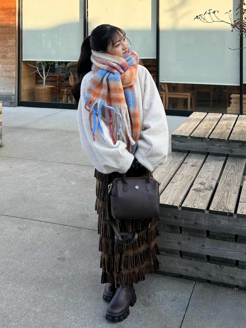 ブラウン系のバッグ、ブラウン系のスカート、ブラウン系のブーツを着用したレディースの冬コーディネートの2枚目の写真