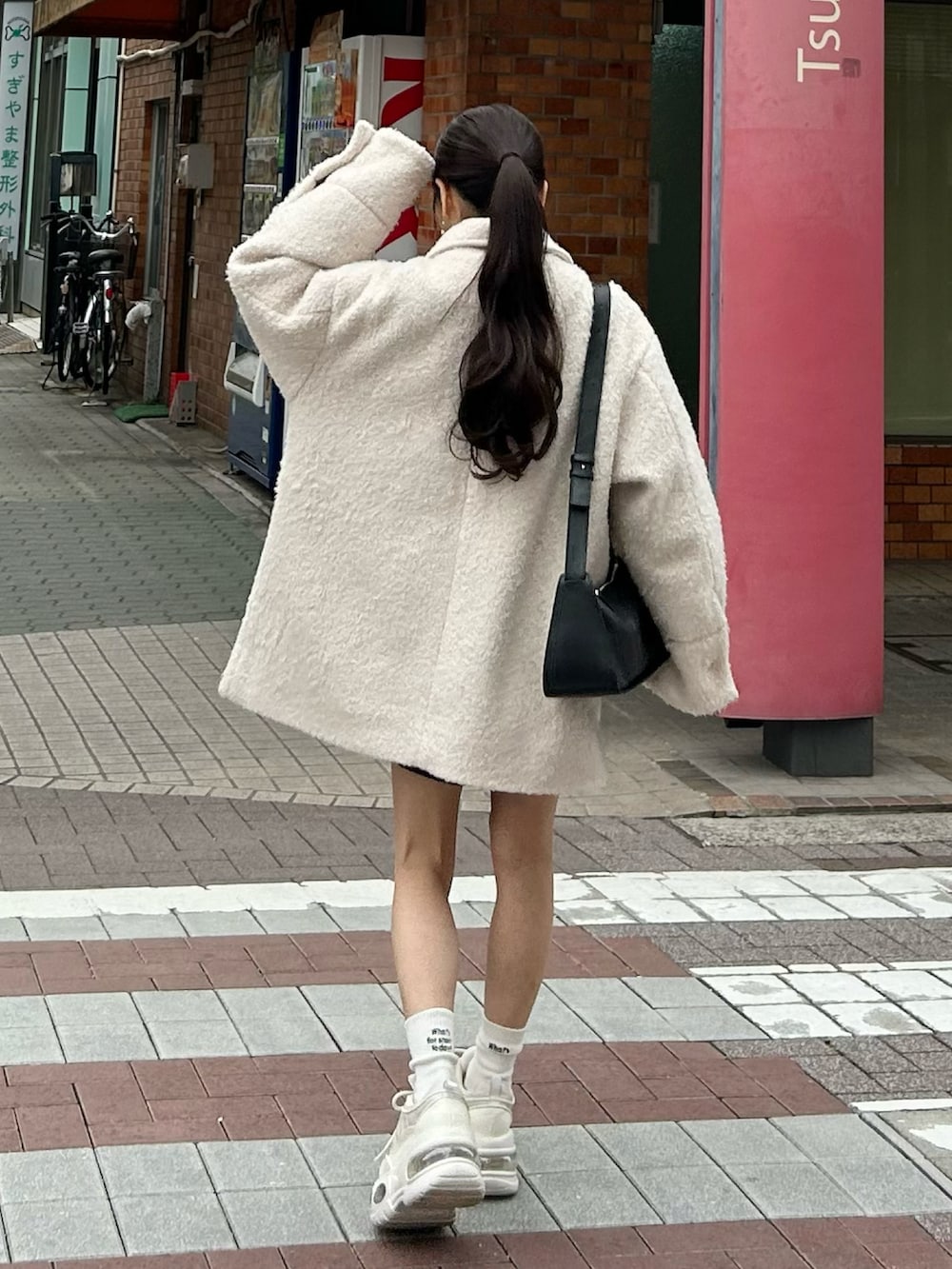 ホワイト系のその他アウター、ブラック系のショルダーバッグ、ホワイト系のスニーカーを着用したレディースの春コーディネートの3枚目の写真