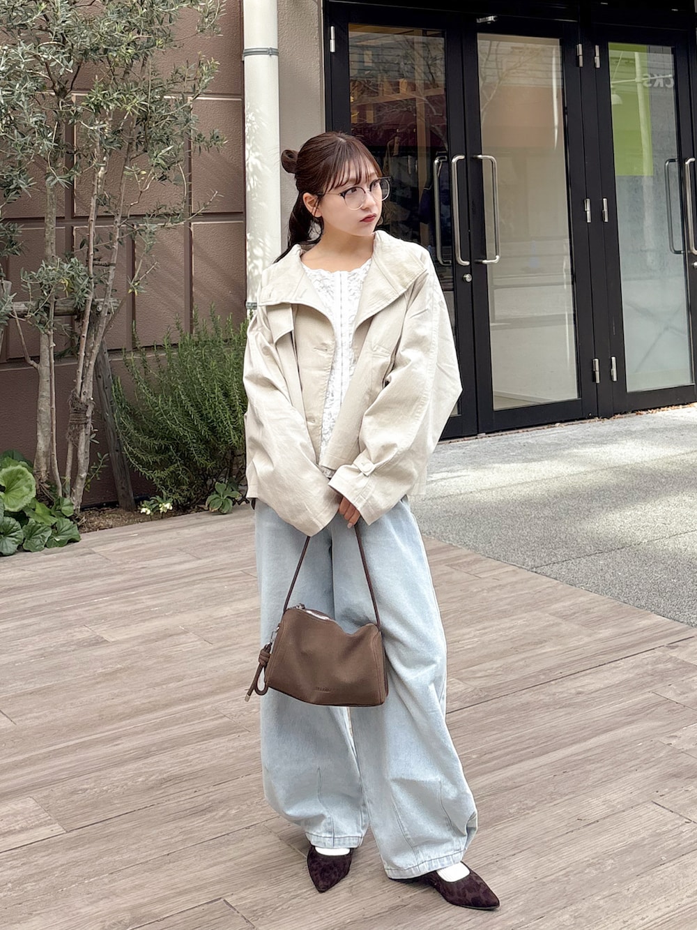 ホワイト系のトレンチコート、ホワイト系のシャツ/ブラウス、ブルー系のデニムパンツを着用したレディースの春コーディネートの3枚目の写真