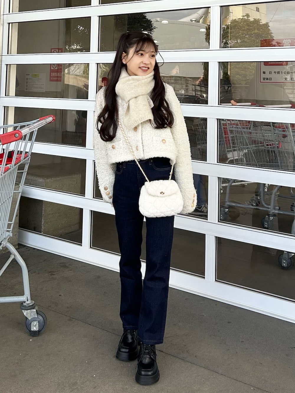 ブルー系のデニムパンツ、ホワイト系のショルダーバッグ、ホワイト系のニット/セーターを着用したレディースの冬コーディネートの2枚目の写真