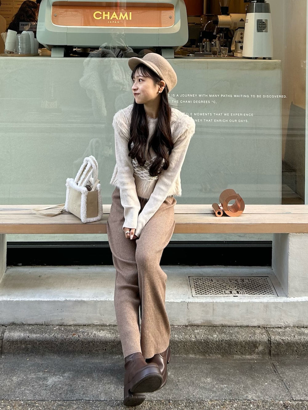 ホワイト系のハンドバッグ、ホワイト系のその他アウター、ブラウン系のブーツを着用したレディースの冬コーディネートの4枚目の写真