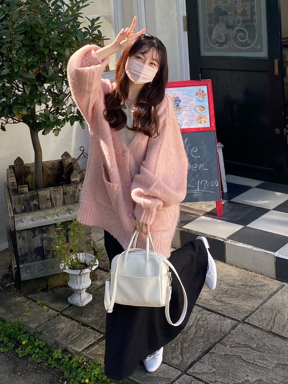 ピンク系のカーディガン/ボレロ、ホワイト系のショルダーバッグ、ブラック系のスカートを着用したレディースの秋コーディネートの2枚目の写真