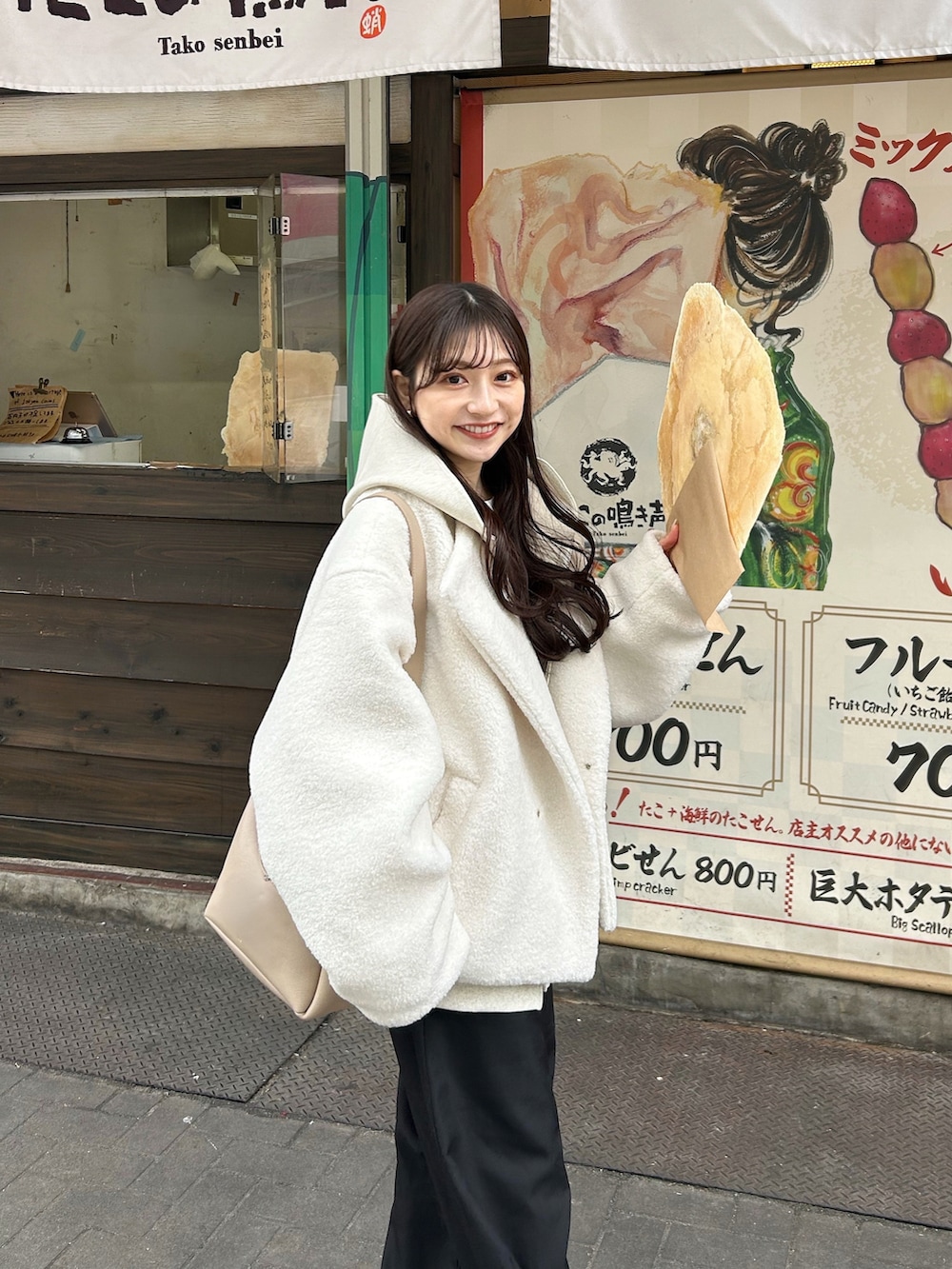 ブラック系のスラックス、ホワイト系のブルゾン、ベージュ系のバッグを着用したレディースの冬コーディネートの2枚目の写真