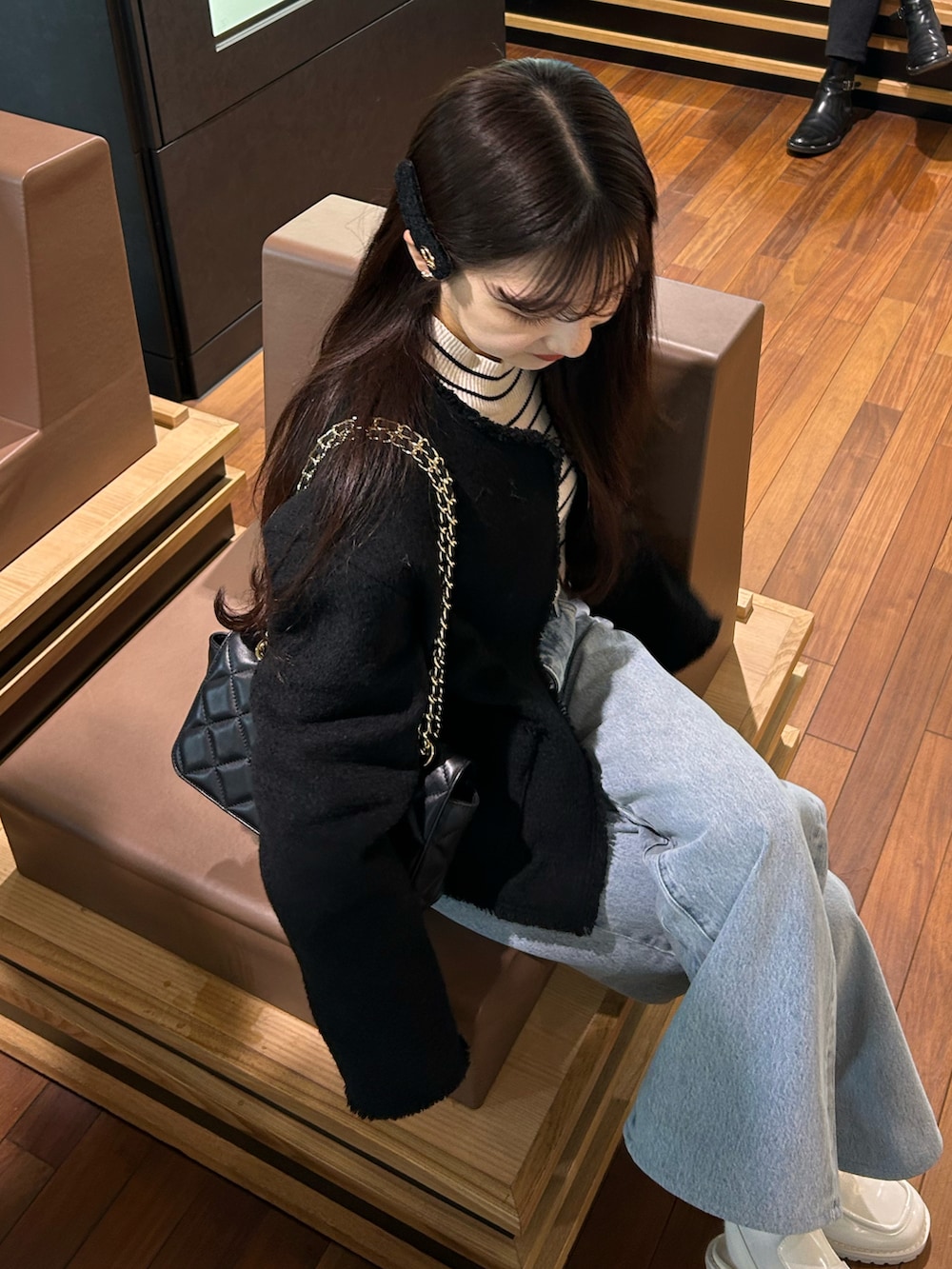 ブルー系のデニムパンツ、ブラック系のジャケット/アウター、ホワイト系のニット/セーターを着用したレディースの春コーディネートの3枚目の写真