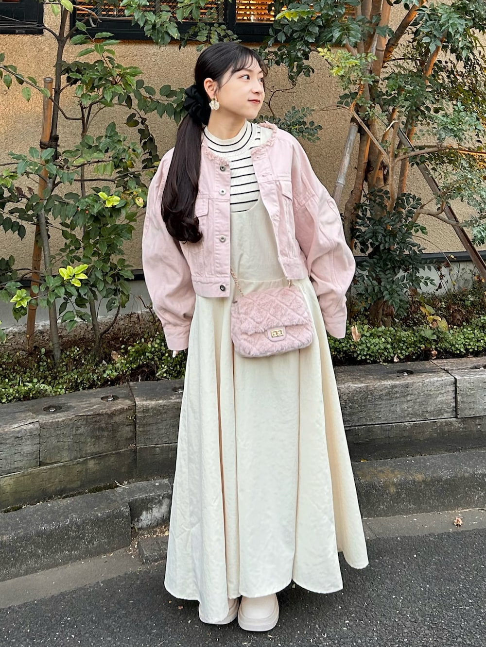 ピンク系のデニムジャケット、ホワイト系のワンピース、ホワイト系のブーツを着用したレディースの冬コーディネートの4枚目の写真