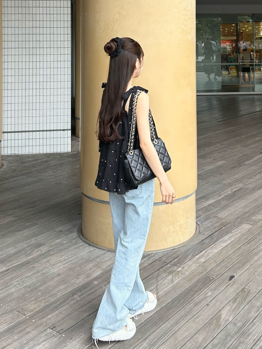 ブルー系のデニムパンツ、ブラック系のトップス、ホワイト系のサンダルを着用したレディースの夏コーディネートの2枚目の写真